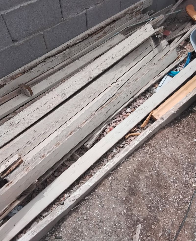 A stack of reclaimed cedar boards leaning against a block wall